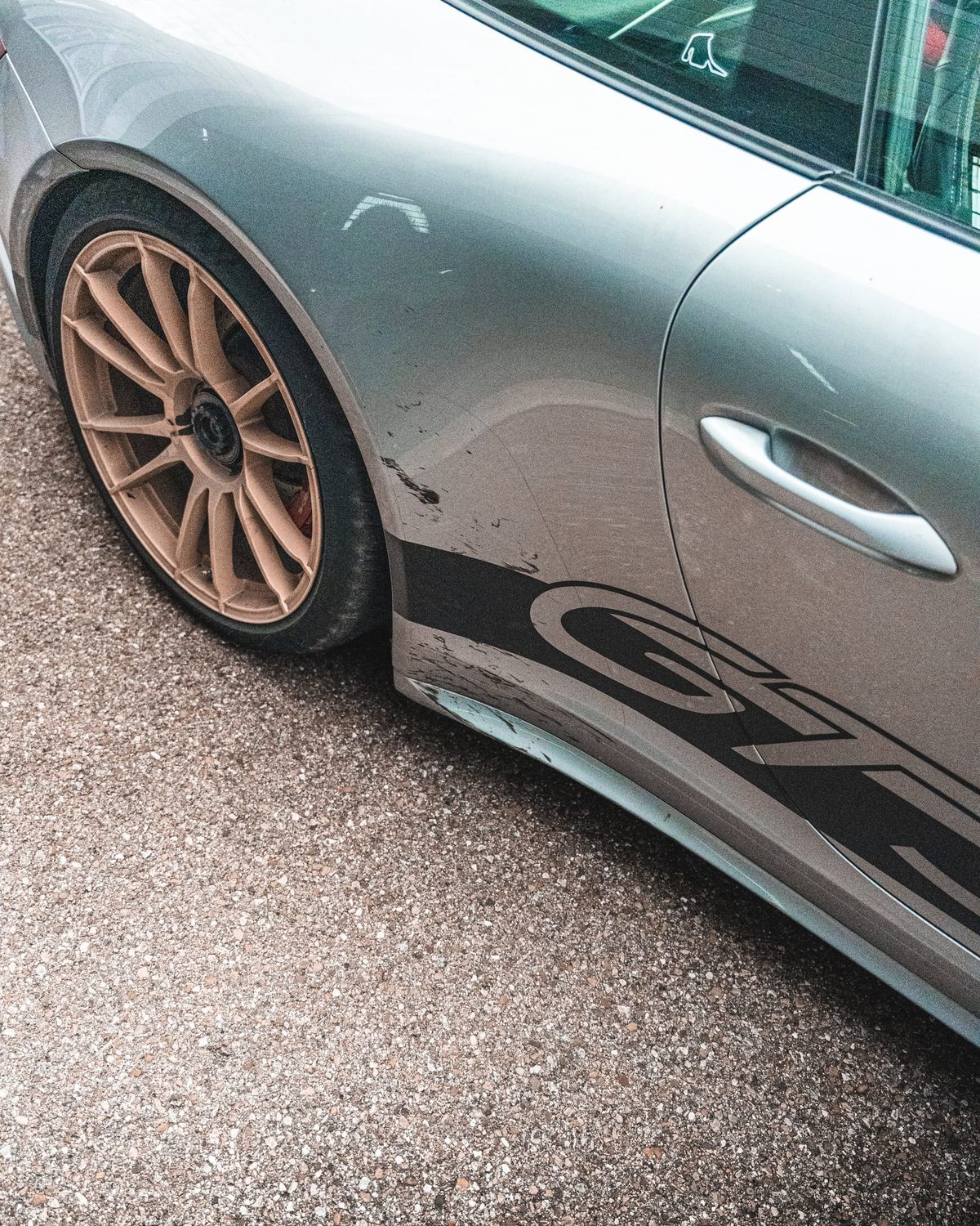 Verschmutzter Schweller und Hinterrad eines silbernen Porsche 911 GT3