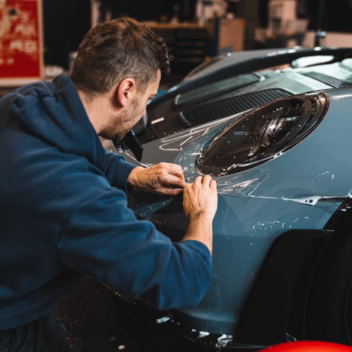 Lackschutzfolie wird an der Scheinwerferkante eines Porsche 911 GT3 RS angelegt
